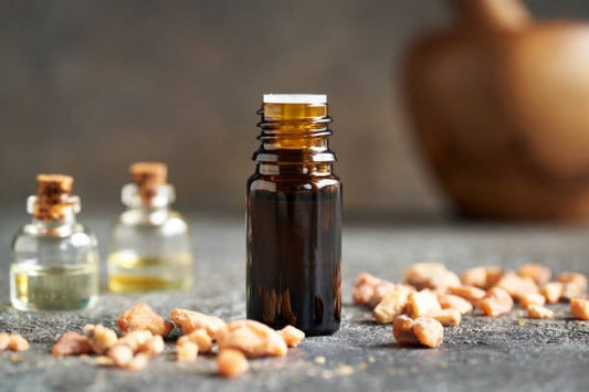 Benzoin essential oil in a dark glass bottle, surrounded by resin pieces and small glass vials.