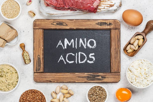 Flat lay of various foods and ingredients with a chalkboard reading 'Amino Acids'.