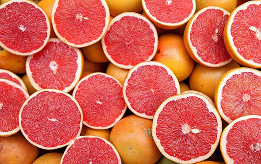 Colorful slices of fresh red grapefruits on a background, showcasing their juicy and vibrant texture.