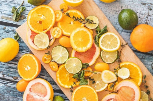 Colorful assortment of citrus fruits including oranges, lemons, and limes on a wooden cutting board.