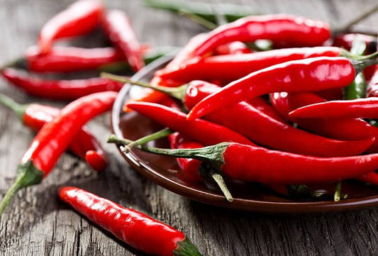 Frisk chili av olika storlekar på en tallrik, symboliserar ökad förbränning och hälsosam livsstil.