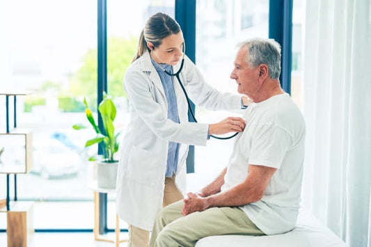 Doctor using a stethoscope on an elderly patient in a bright clinic setting.