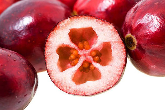 Close-up of fresh cranberries, showcasing the vibrant red skin and inner seed structure.