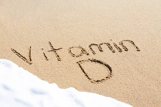Sand with the words 'Vitamin D' written on it, symbolizing sunlight and vitamin synthesis.