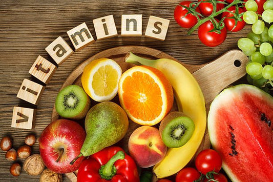 Colorful assortment of fruits and vegetables arranged with blocks spelling 'vitamins', symbolizing health and nutrition.