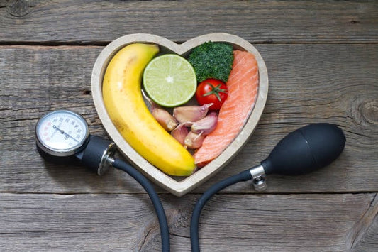 Healthy foods in a heart shape with a blood pressure monitor, promoting heart health.