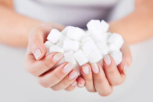 A person holding a pile of white sugar cubes in their hands.