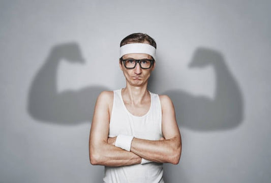 Man in workout clothes flexing with strong arm shadows, representing fitness and strength training.