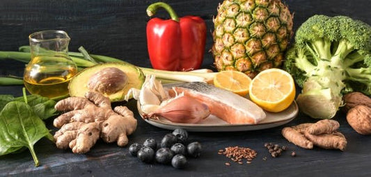 A vibrant assortment of anti-inflammatory foods including salmon, broccoli, pineapple, and ginger arranged on a plate.