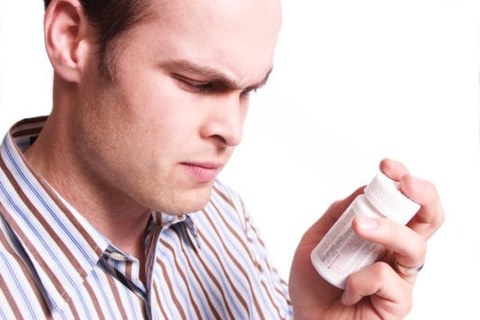 Man studying a bottle of testosterone supplement with a concerned expression.