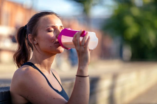 Kvinna som dricker en proteinshake efter träning för att stödja viktminskning och öka proteinintaget.