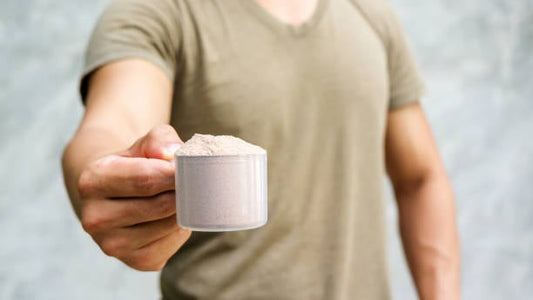 En man håller en skopa med isolat proteinpulver, redo att användas i träning och kost.
