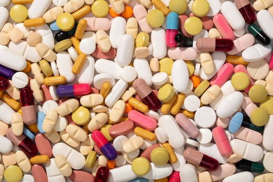 Färgglada kosttillskott och vitaminer spridda över en yta, representerar dagligt intag för hälsa.