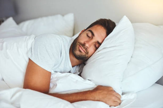 Man sleeping peacefully in a bed surrounded by plush pillows.