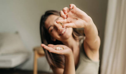 Woman holding vitamins and supplements, smiling happily to promote healthy morning routines.