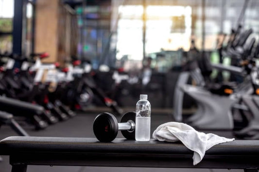 Dumbbell and water bottle on gym bench, ready for a workout session.