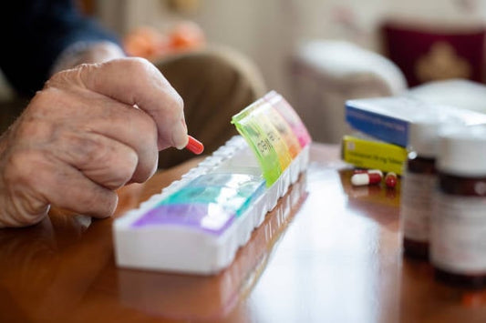Person organizing daily medications with a pill organizer and various prescription bottles.