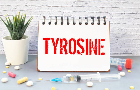 Notebook with 'TYROSINE' written on it, surrounded by pills and a syringe.