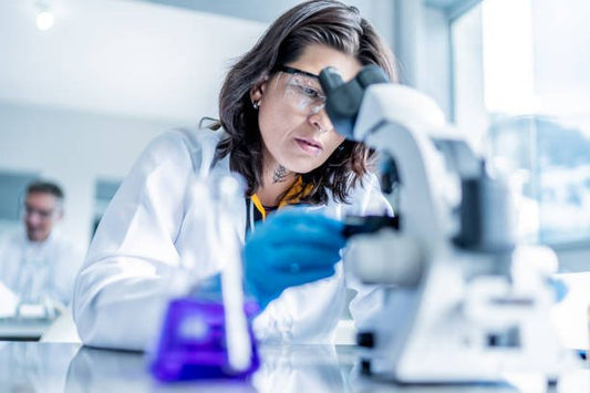 Scientist examining samples under a microscope in a modern laboratory setting.