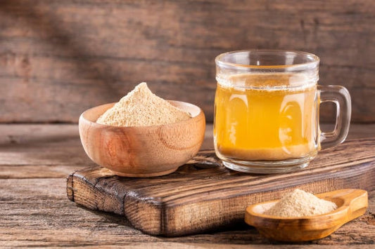 Bowl of macapulver with a glass of macalatte on a wooden surface, showcasing its health benefits.