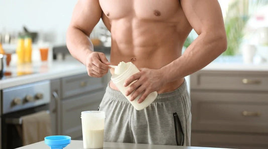 Muscular man preparing a mass gainer supplement in the kitchen.