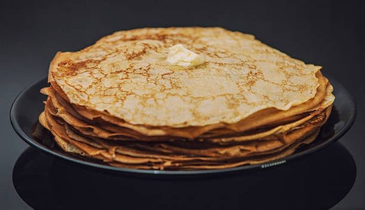Tall stack of healthy pancakes topped with butter, perfect for boosting protein intake.