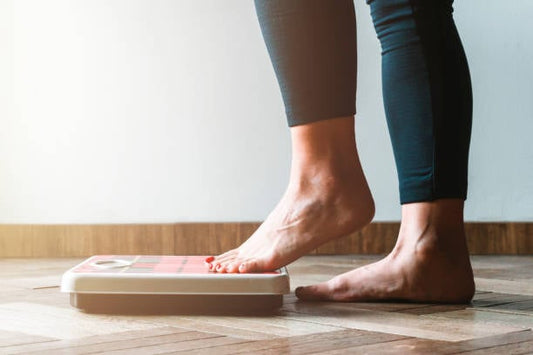 Person stepping onto a weighing scale, symbolizing weight loss and health management.