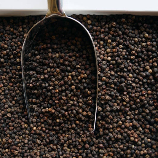 Munkpeppar seeds with a metal scoop on a dark textured background.