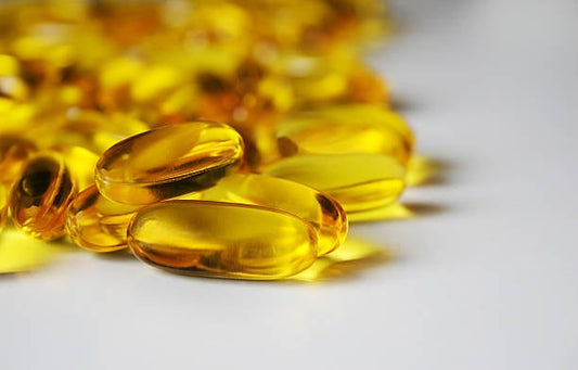 Close-up of yellow omega-3 fish oil capsules on a white background.