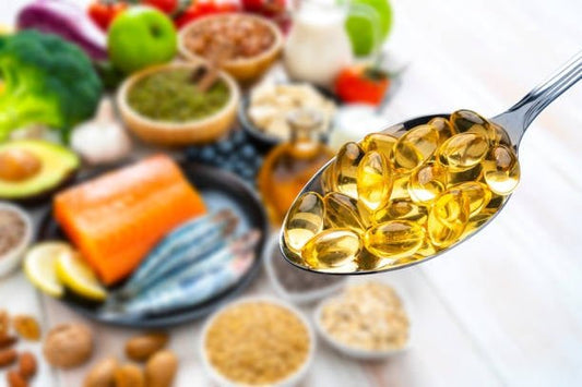 Spoonful of omega-3 capsules with a healthy assortment of foods in the background.