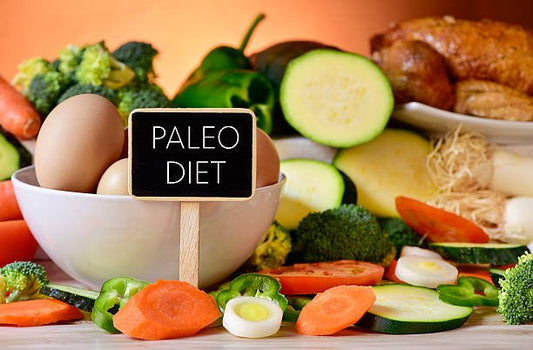 En skål med ägg och färska grönsaker med en skylt som säger 'Paleo Diet' på ett träbord.
