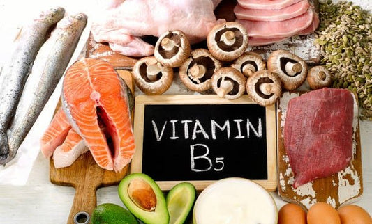 Variety of foods rich in Vitamin B5 including fish, meats, mushrooms, and eggs on a rustic board.