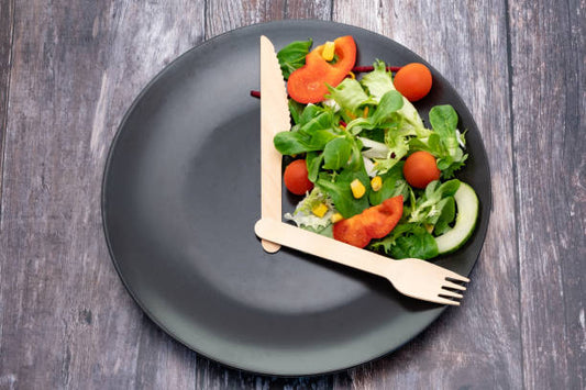 Salad on a plate shaped like a clock, symbolizing intermittent fasting and healthy eating.