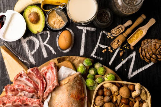 A variety of protein-rich foods including meat, dairy, nuts, and legumes, with the word 'PROTEIN' written in chalk.