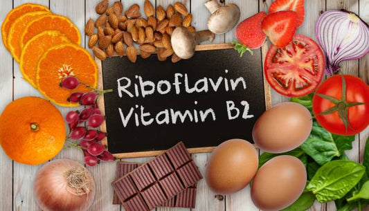 Riboflavin and Vitamin B2 foods including fruits, vegetables, nuts, eggs, and chocolate on a wooden background.