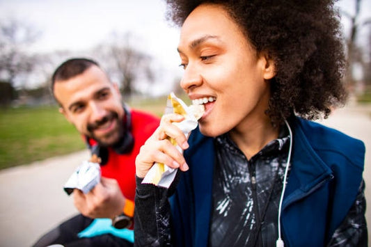 Två personer njuter av proteinbars utomhus, perfekt för energitillskott efter träning.