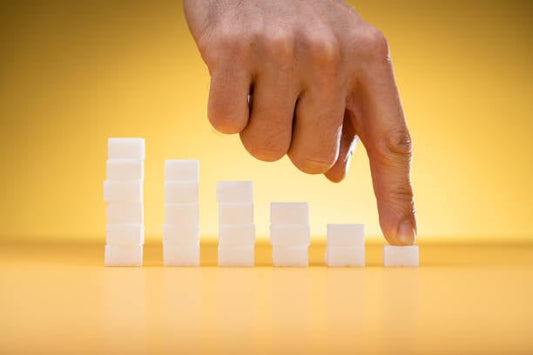 Hand pointing at stacked sugar cubes representing blood sugar levels.