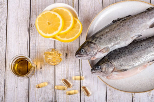 Fresh fish with lemon slices, fish oil capsules, and a glass of oil on a wooden background.