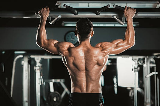 Man performing pull-ups in a gym, showcasing muscular back strength and fitness training.