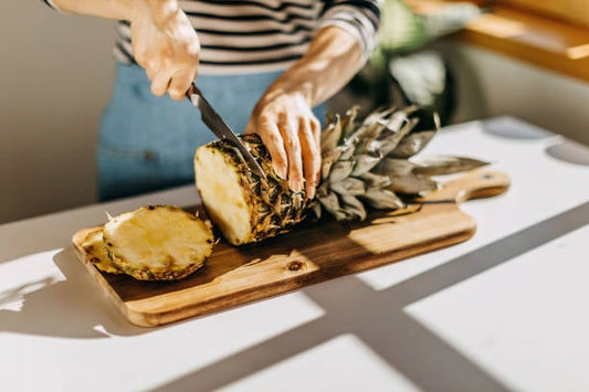 Person skär en färsk ananas på en skärbräda, vilket illustrerar ananasdietens fokus på frukten.