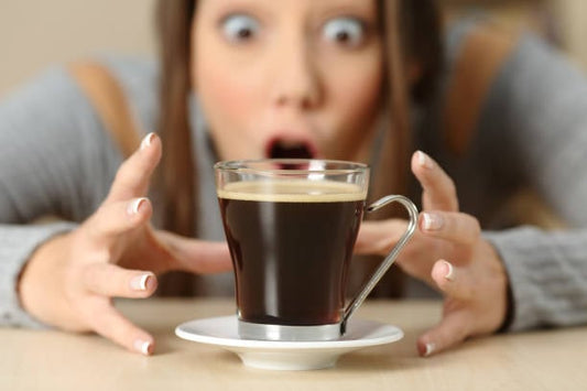 Woman in awe reaching for a cup of coffee, highlighting caffeine's stimulating effects.