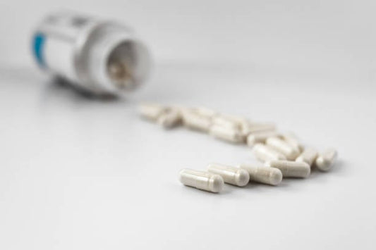 Öppnad flaska med lithium orotate-kapslar och några kapslar utlagda på en yta.