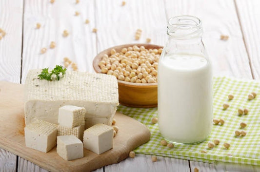 Tofu, soy milk, and soybeans displayed on a wooden surface, showcasing plant-based protein options.