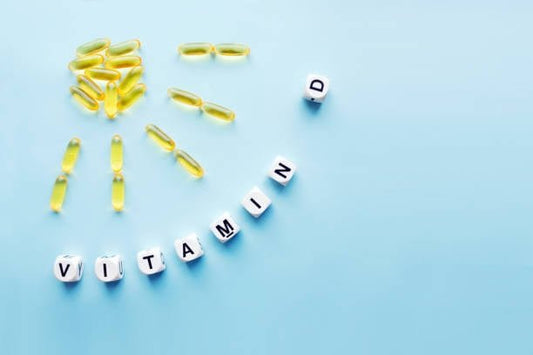 Kapslar av D-vitamin formade som en sol med bokstäver som stavar 'VITAMIN D' på en blå bakgrund.