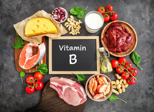 Assortment of foods rich in Vitamin B, including meat, fish, cheese, nuts, and vegetables on a dark background.