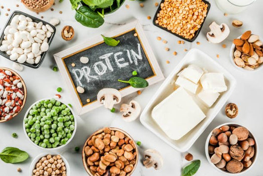 Ett urval av växtbaserade proteinkällor som bönor, linser och tofu med en tavla som visar ordet protein.