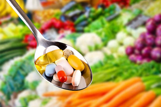 Spoonful of various dietary supplements with fresh vegetables in the background, highlighting health choices.