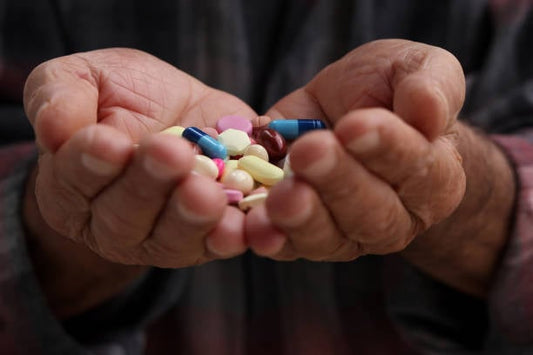 Person holding a variety of colorful dietary supplements in both hands, representing health choices.