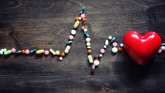 Pills arranged as a heartbeat line with a red heart, representing health and wellness.