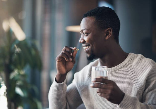 Man taking vitamins with a glass of water, promoting health and wellness.